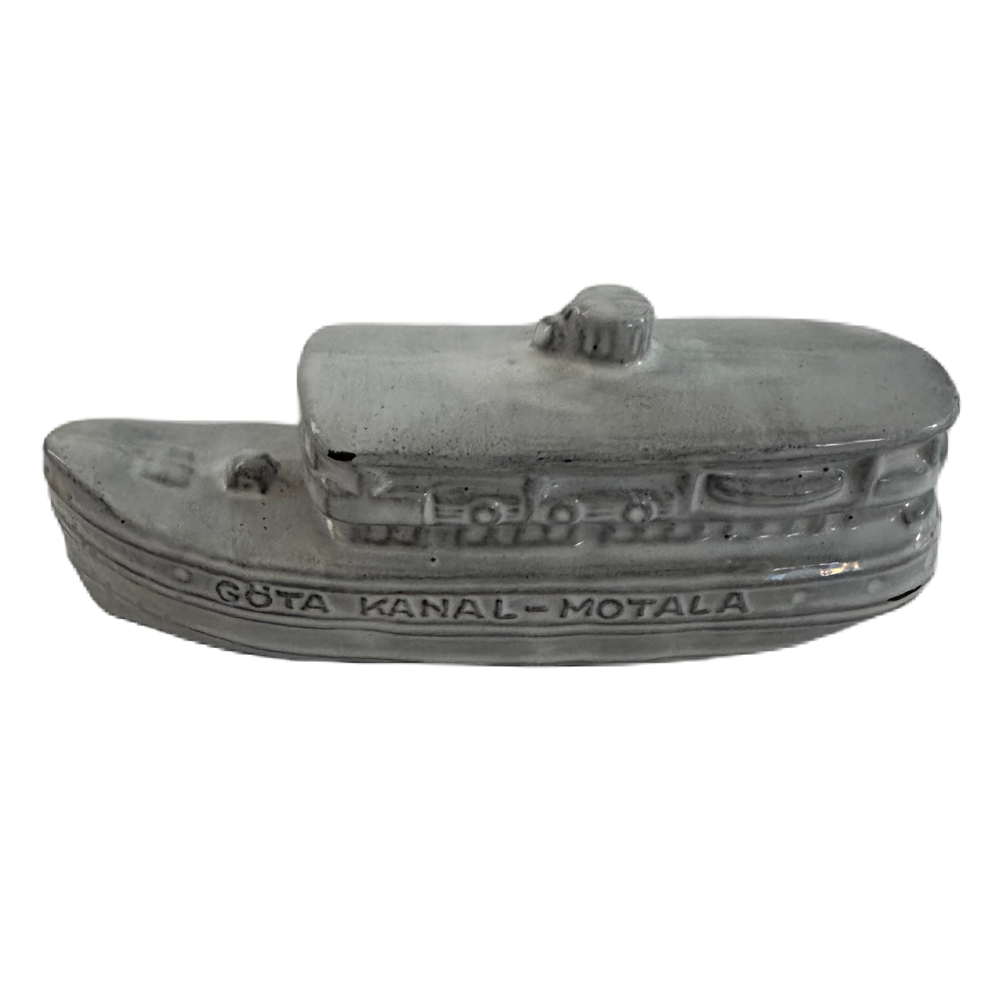 Figurin från Norrmans keramikverkstad föreställandes en grå båt med texten Göta Kanal Motala.