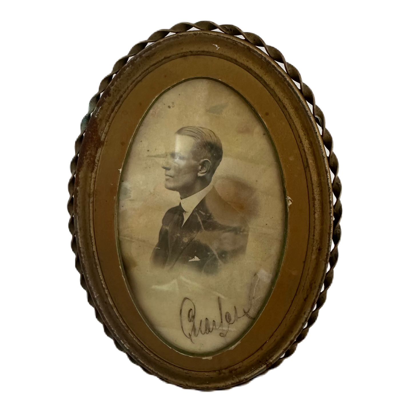 Oval, mässingsfärgad tavla med patina innehållande ett fotografi på en man från svunna tider.