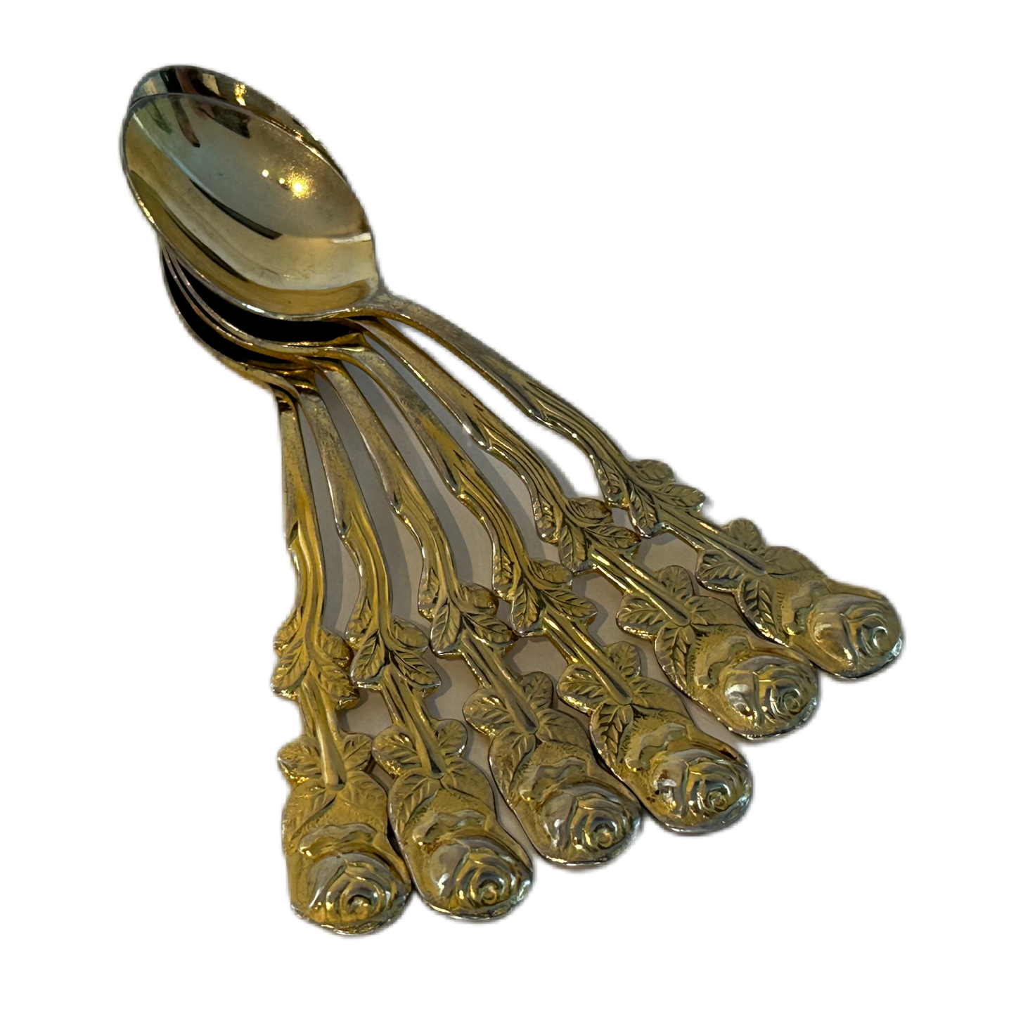 Guldfärgade teskedar i rostfritt stål med dekorativ utsmyckning, föreställandes en ros.