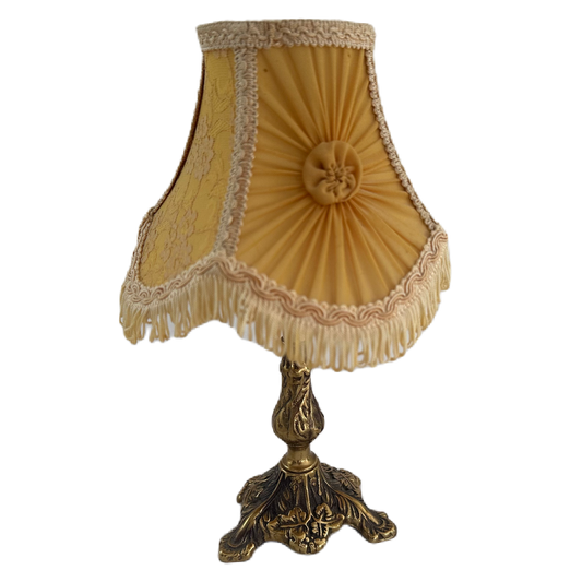 Bordslampa med mässingsfärgad lampfot samt klassisk lampskärm med fransar i gul och beige.