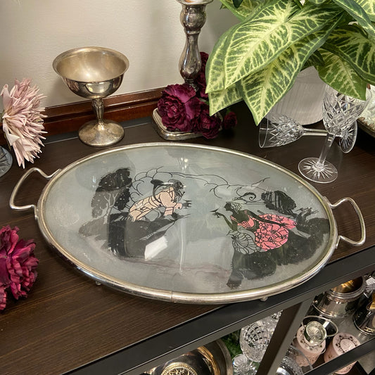 Oval, silverfärgad glasbricka med motiv.