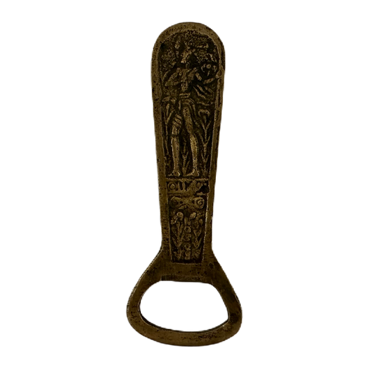 Flasköppnare i mässingsfärg med motiv av figurer.