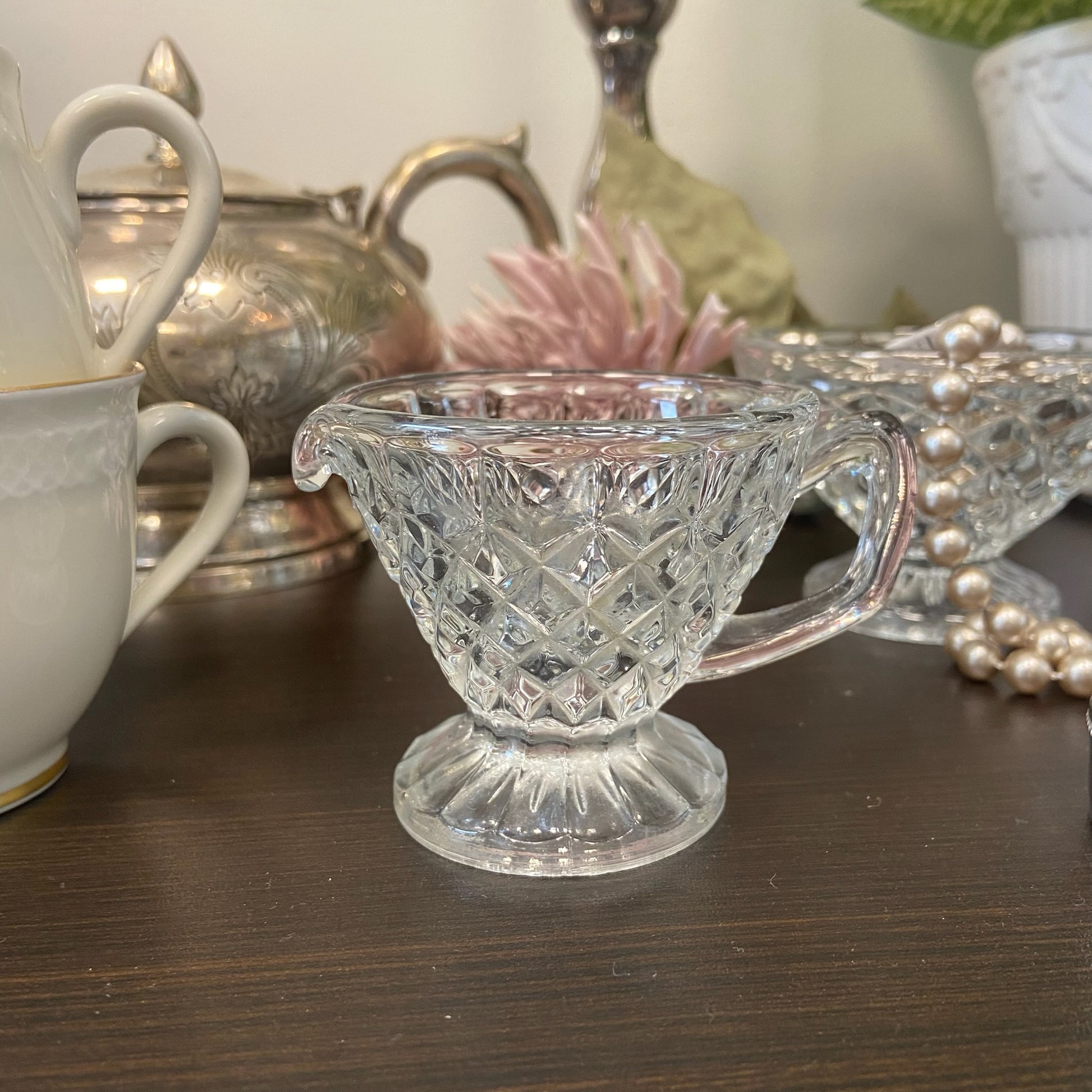 Liten diamantmönstrad gräddkanna på fot i glas.
