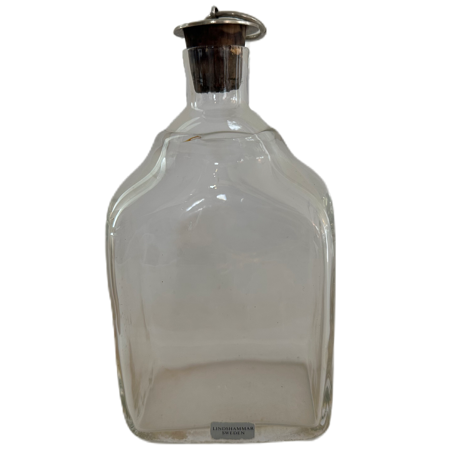 Etikettmärkt plunta i transparent glas med propp i kork och metall från Lindshammar Sweden.