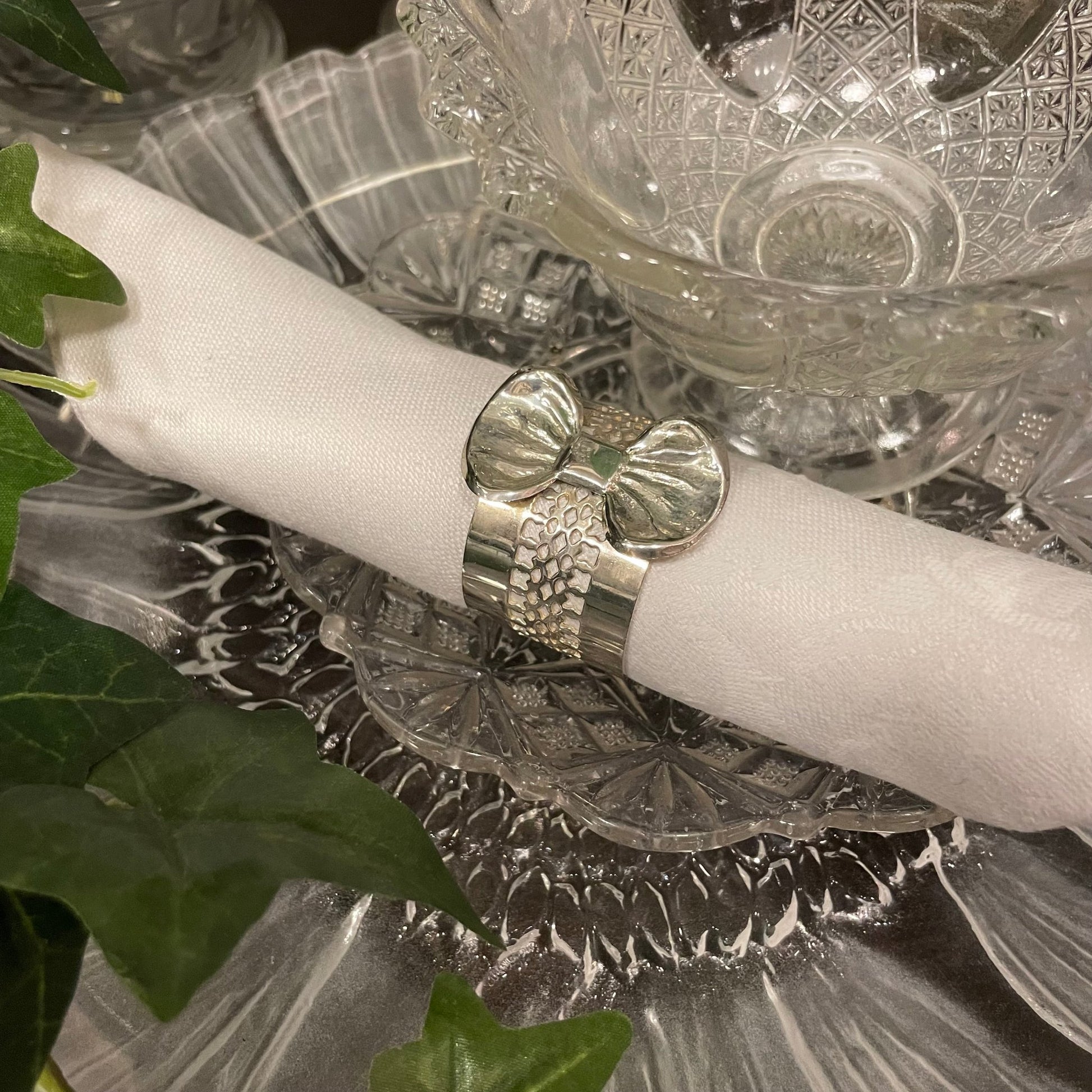 En silverfärgad servettring med rosett och genombruten dekor.