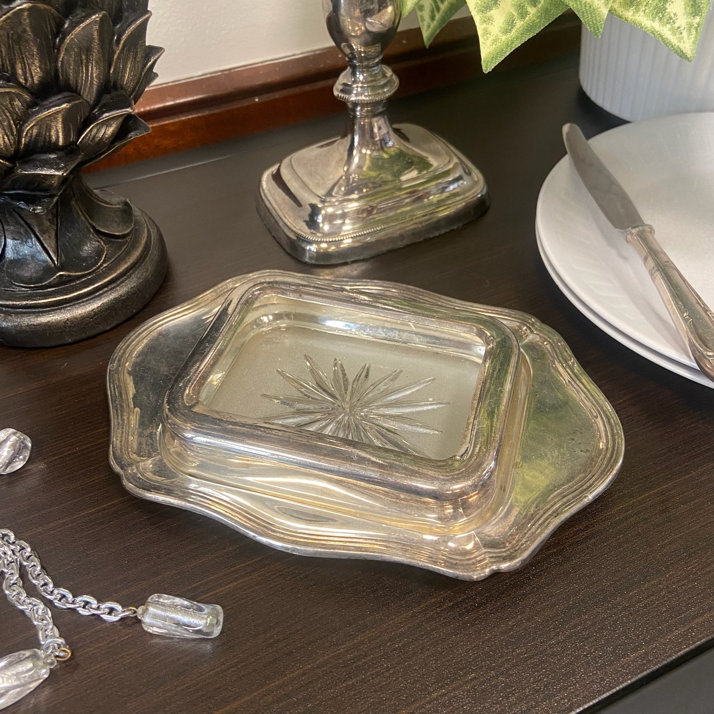 Smörbytta i glas med metallfat och metallram.