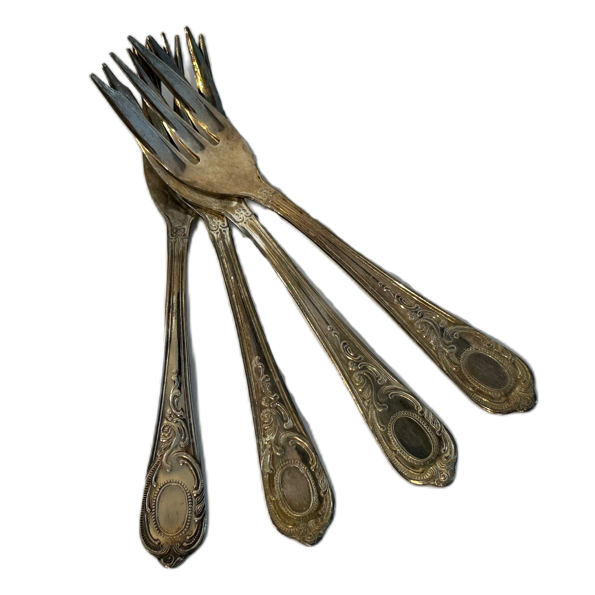 Små, silverfärgade tårtgafflar med dekor.