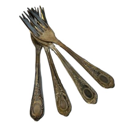 Små, silverfärgade tårtgafflar med dekor.