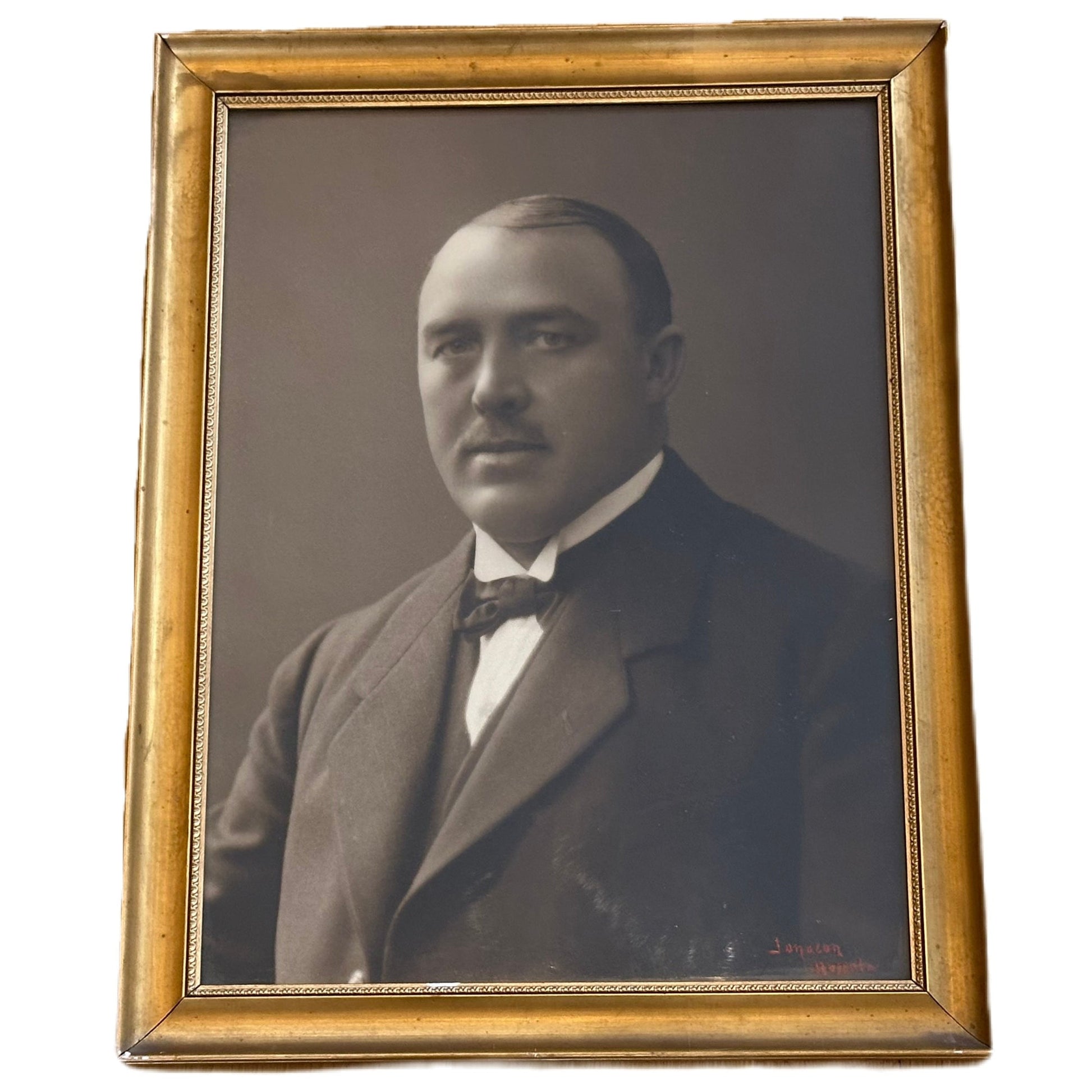 Tavla med ett svartvitt fotografi föreställande en välklädd man.