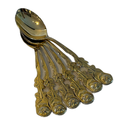 Guldfärgade teskedar i rostfritt stål med dekorativ utsmyckning, föreställandes en ros.